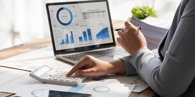 Business woman using calculator to calculate financial report working at office with laptop computer on table Asian female accountant or banker making calculations finances and economy concept