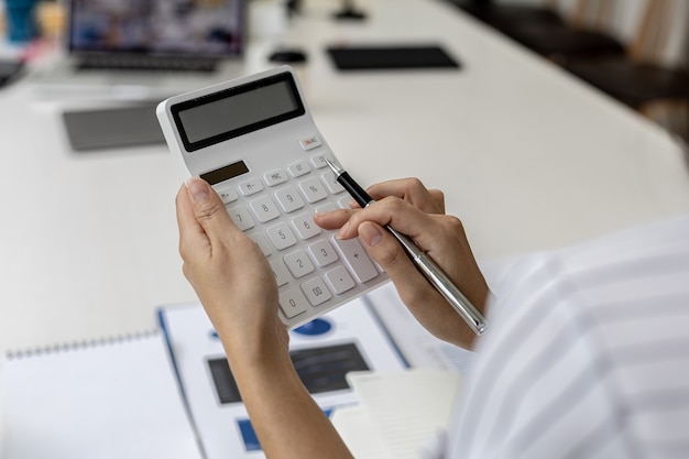 電卓を使用して会社の財務書類の数値を計算するビジネスウーマンは、過去の財務データを分析して会社の成長方法を計画しています。財務コンセプト。