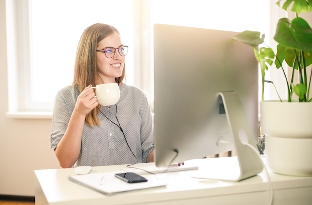Business woman using computer at home, office, cup of caffe.