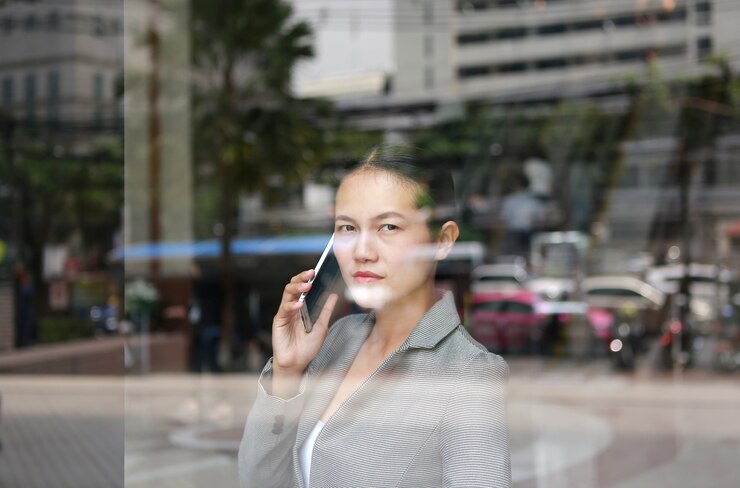 Photo business woman using a smartphone at reflection glass of office building.