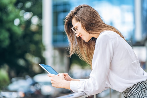 Business woman using tablet near modern business center.