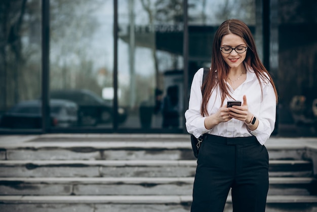 Photo business woman walking down the stairs and using phone