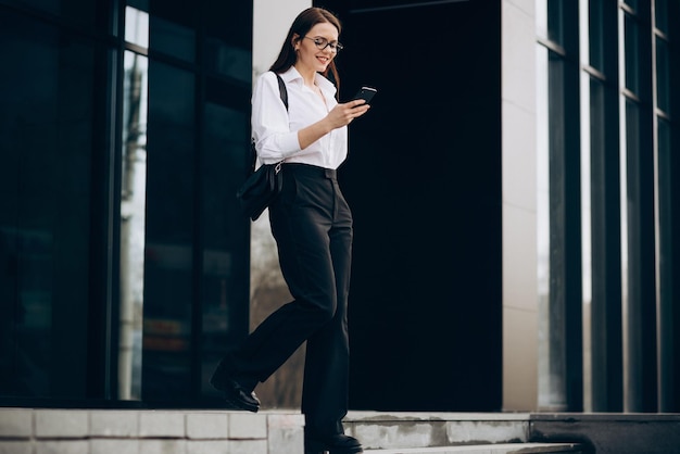 Photo business woman walking down the stairs and using phone