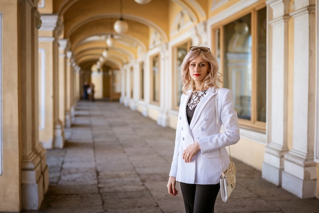 A business woman in a white jacket stands on the street