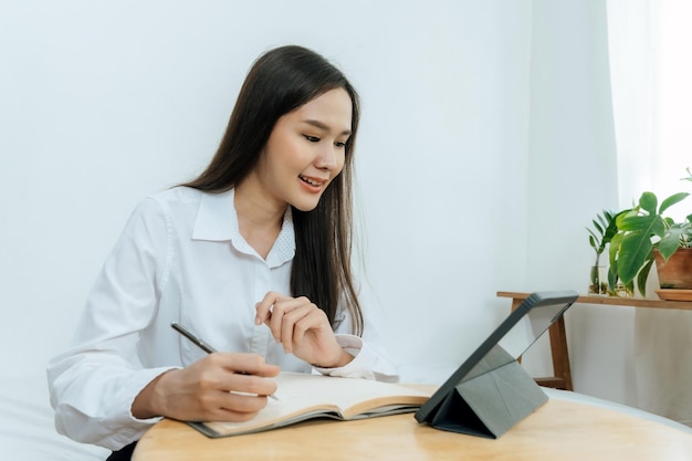 Foto donna d'affari in camicia bianca che lavora e calcola le finanze con il rapporto del documento e la tavoletta mobile digitale sulla scrivania a casa dell'ufficio marketing online digitale e concetto di business finanziario