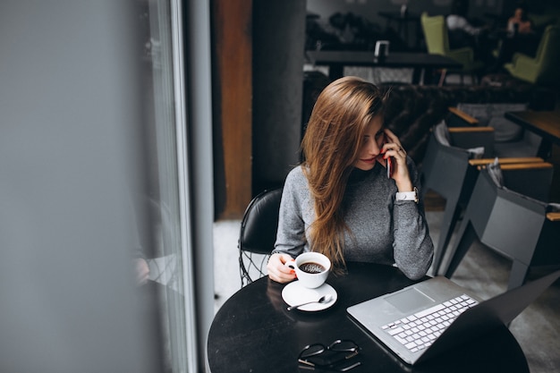 Business woman with coffee in a cafe working on computer