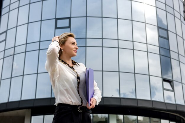 Business woman with folder standing outside office building