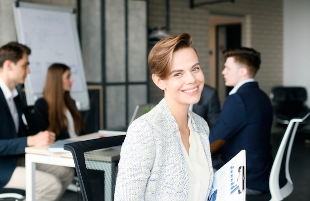 Business woman with her staff, people group in background at modern bright office indoors