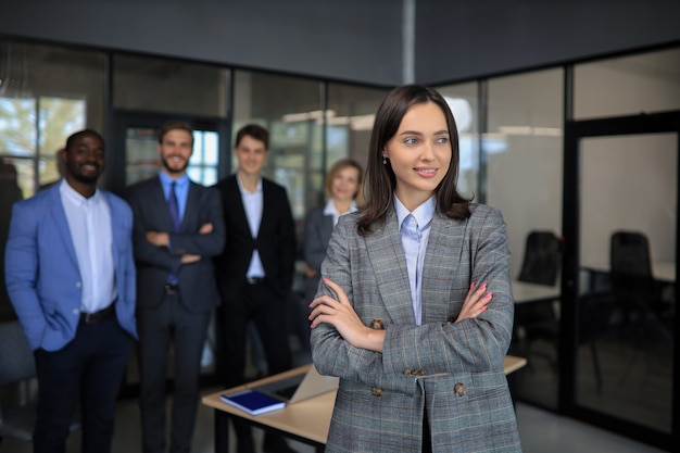 Business woman with her staff, people group in background at modern bright office indoors.