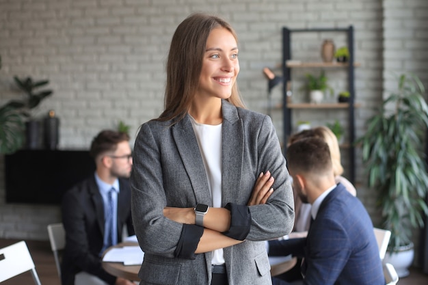 Business woman with her staff, people group in background at modern bright office indoors.