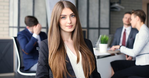 Business woman with her staff, people group in background at modern bright office indoors