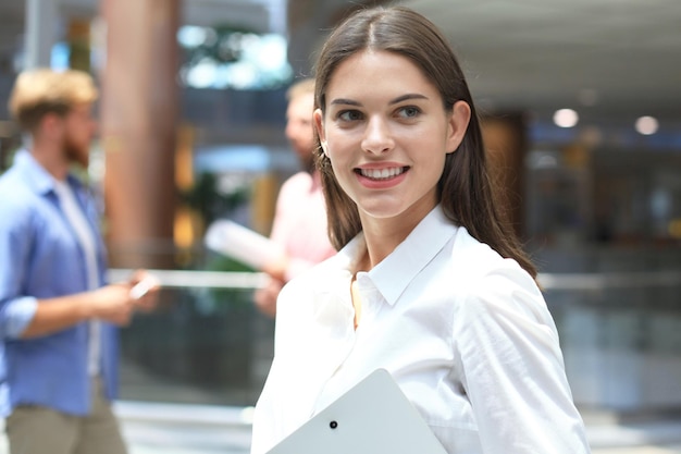 Business woman with her staff, people group in background at modern bright office indoors