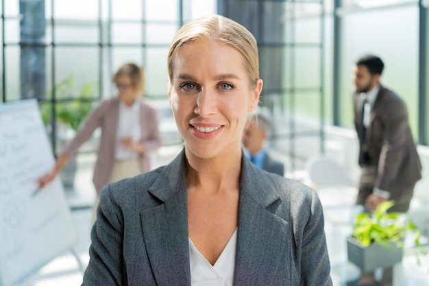 Business woman with her staff people group in background at modern bright office indoors