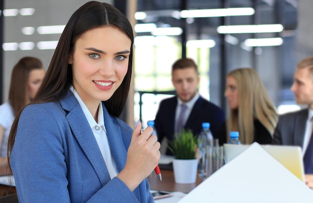 Business woman with her staff people group in background at modern bright office indoors