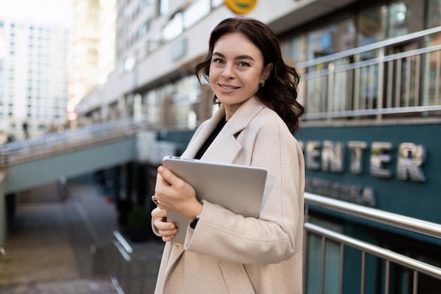 Деловая женщина с ноутбуком в руках на фоне города