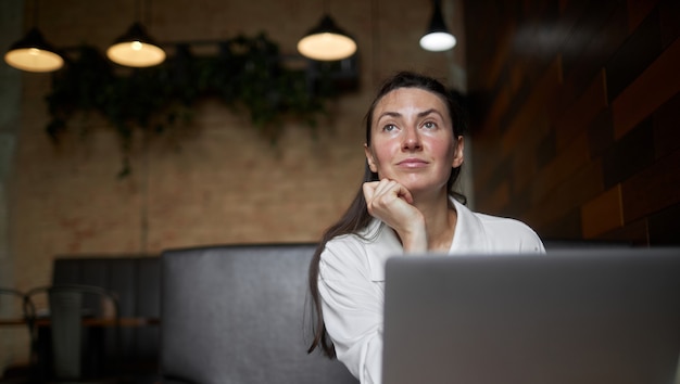 Business woman with laptop. She is working and relaxing at a cafe drinking latte