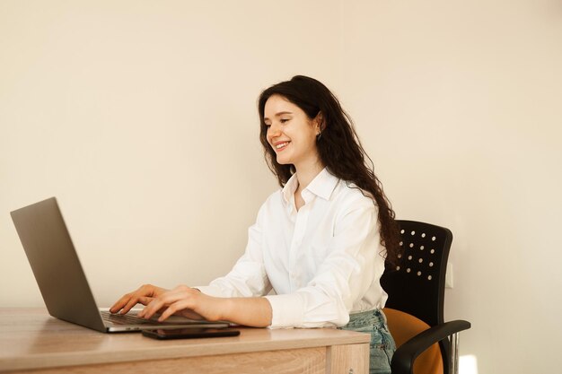 Business woman with laptop working online at freelance work Attractive girl watching online video tutorial about designer work