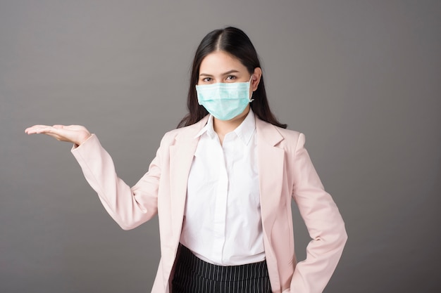 Business woman with mask is showing something on her hand