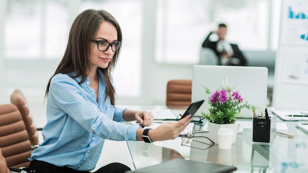 Donna d'affari con uno smartphone sul posto di lavoro in un ufficio moderno