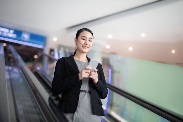 Business Woman with suit Uses Smart phone in terminal