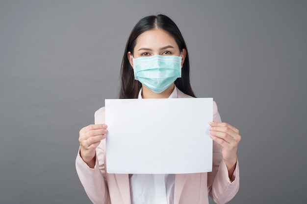 Деловая женщина с хирургической маской держит чистый лист бумаги