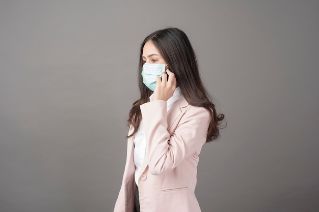 Business woman with surgical mask is using cell phone