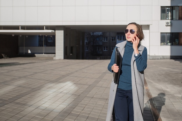 Business woman with tablet and phone going in the autumn city