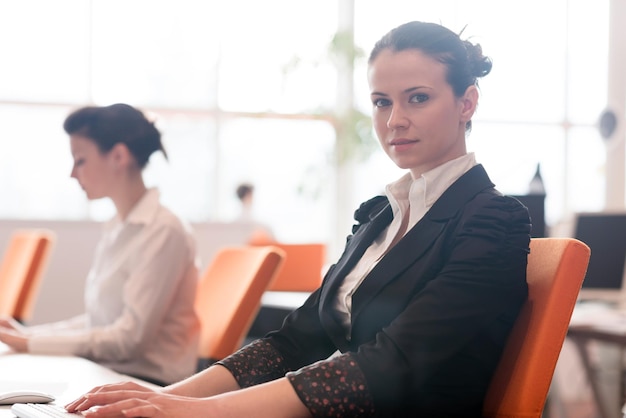 business woman working on desktop computer at modern startup office, people group in background