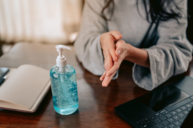 Business woman working from home wearing protective mask\
working from home cleaning her hands