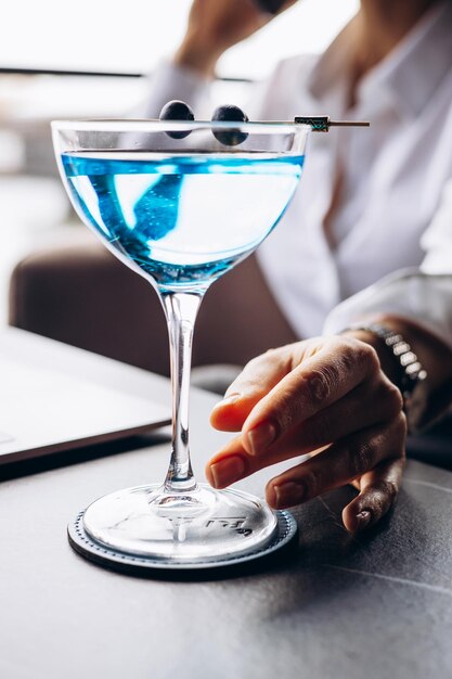 カフェでノートパソコンに取り組み、カクテルを飲むビジネスウーマン