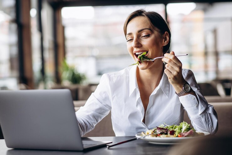 Photo ビジネスの女性のラップトップに取り組んでサラダを食べる