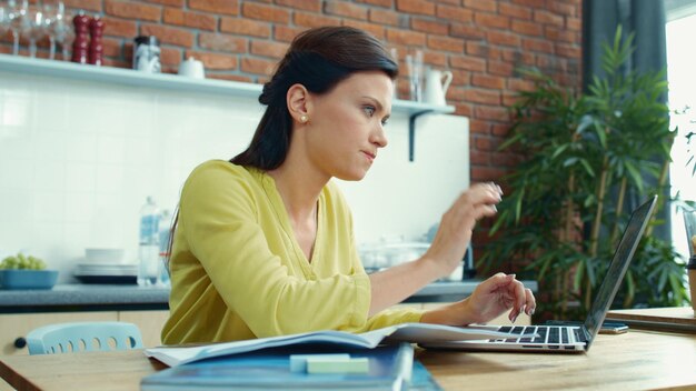 Business woman working on laptop at home Annoyed girl taking break in kitchen