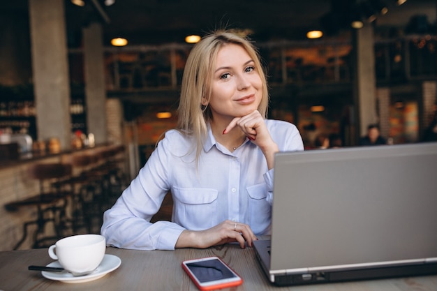 Деловая женщина, работающая на ноутбуке и телефоном в кафе