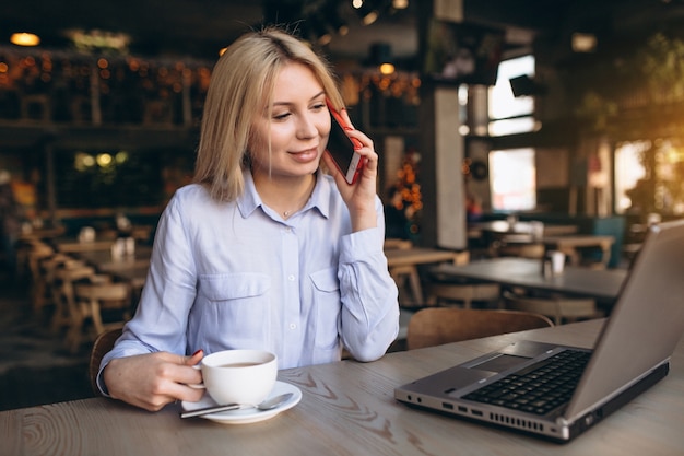 Business woman working on laptop and phone in a cafe