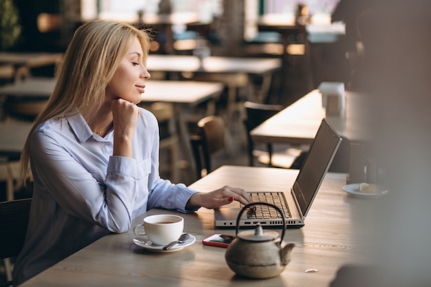 Business woman working on laptop and phone in a cafe