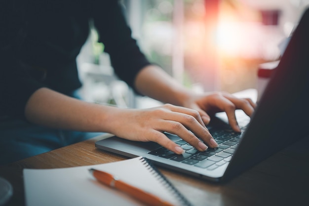 business woman working on laptop while sitting in creative office or cafe. young girl working with laptop on the wood table in the cafe.