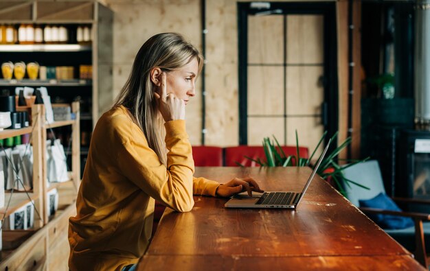 Business woman working on a laptop while sitting at a table in a coffee house