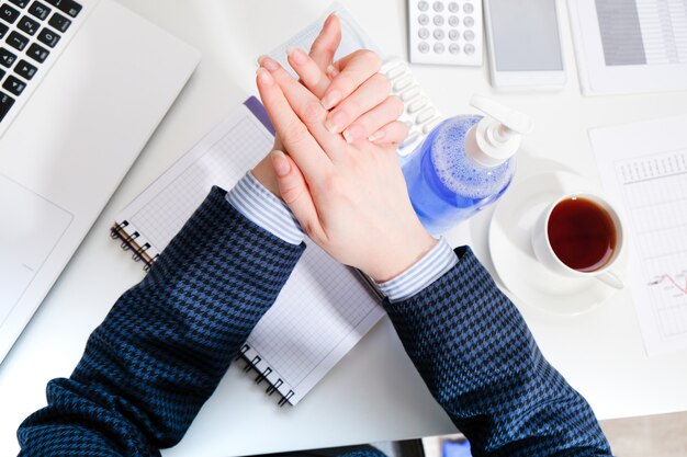 business woman in the workplace washes her hands with gel