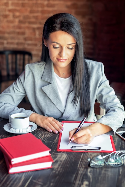 Scrittura della donna di affari in caffè