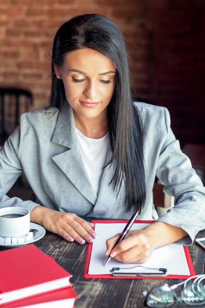 Scrittura della donna di affari in caffè