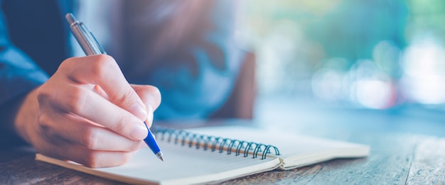 Photo business woman writing on a notepad with a pen in the office.