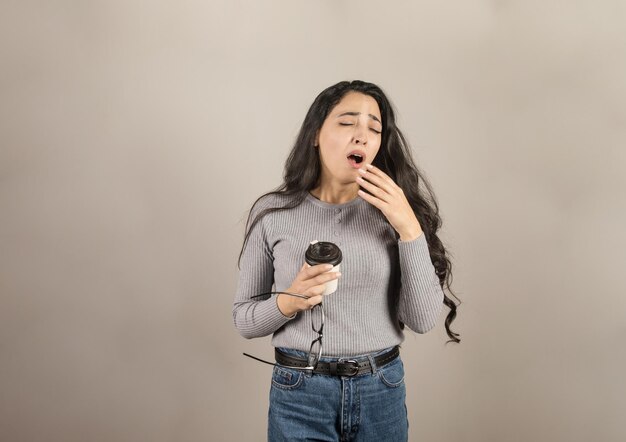 Business woman yawns while holding coffee