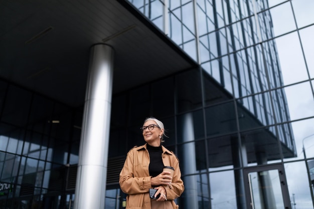 Деловая женщина лет на фоне огромного офисного небоскреба