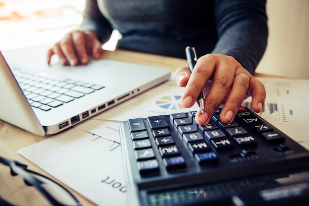 Business women are using a calculator to calculate the income of the business.