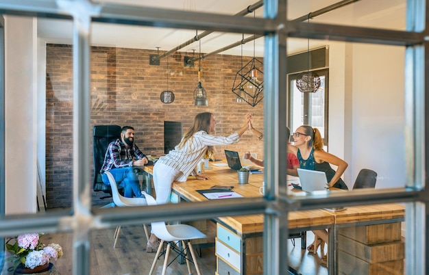 Photo business women celebrating a success high-fiving hands in the office