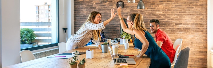 Photo business women celebrating a success highfiving in the office