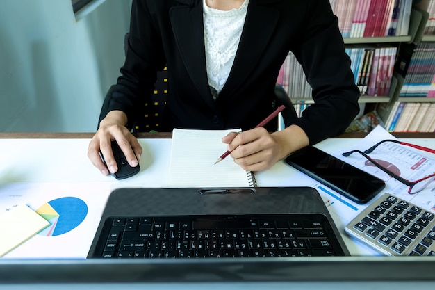 ビジネス、女性コンピュータでノートブックのラップトップを使用してグラフで紙を書くと、クローズアップ手。