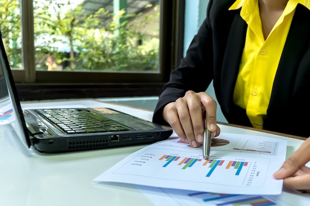 Business women Close-up hand with paper writing at graph.