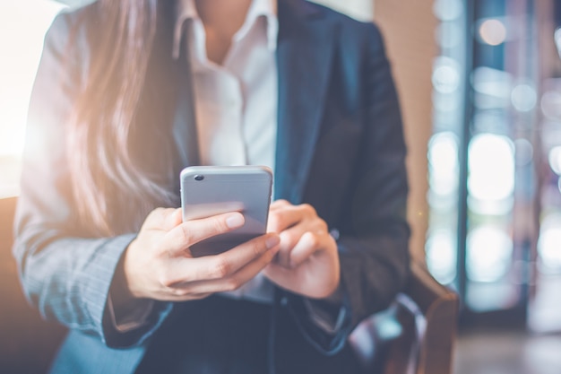 La mano delle donne di affari sta usando lo smartphone.