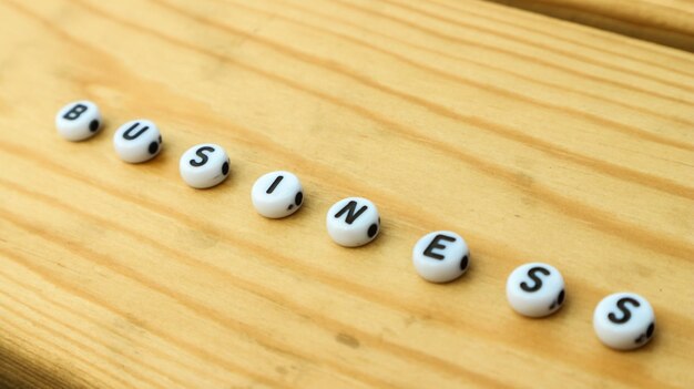 ДЕЛОВОЕ слово, сделанное из словесных бусин, изолированных на деревянном столе Текстовый дизайн
